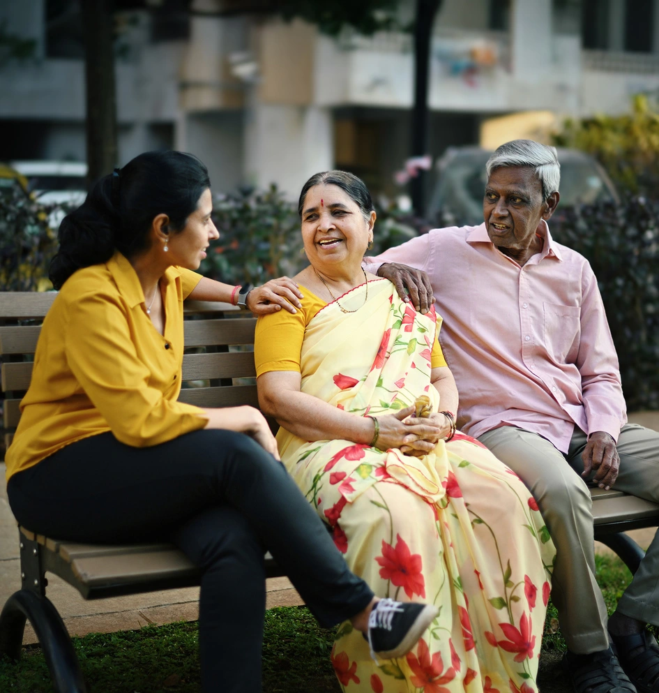 Adult daughter talking to her senior parents on a bench in a park