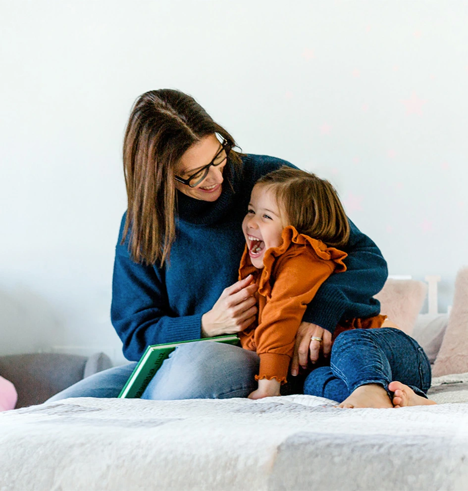 Mother and daughter cuddling on a bed in a kids room