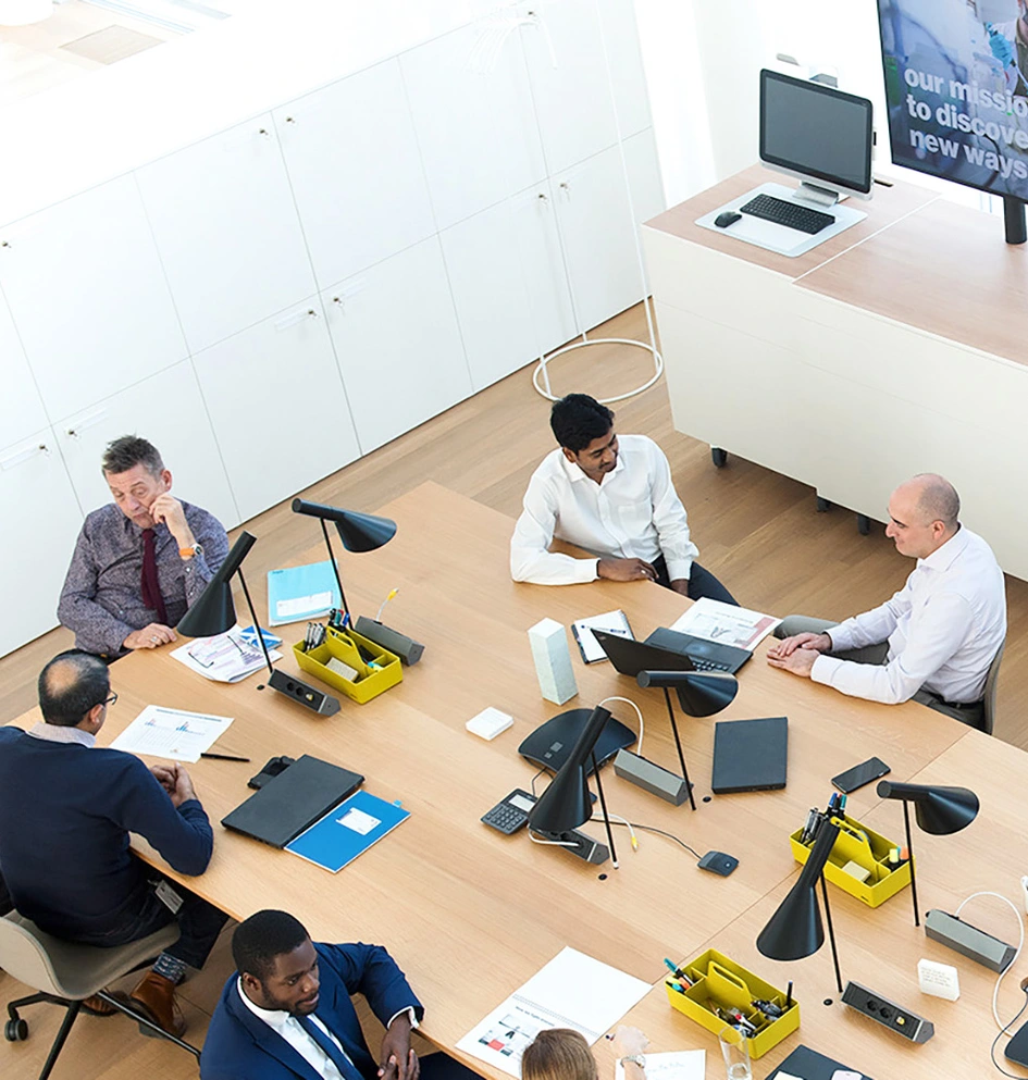 Overhead view of a meeting room with people in the foreground and screens in the background