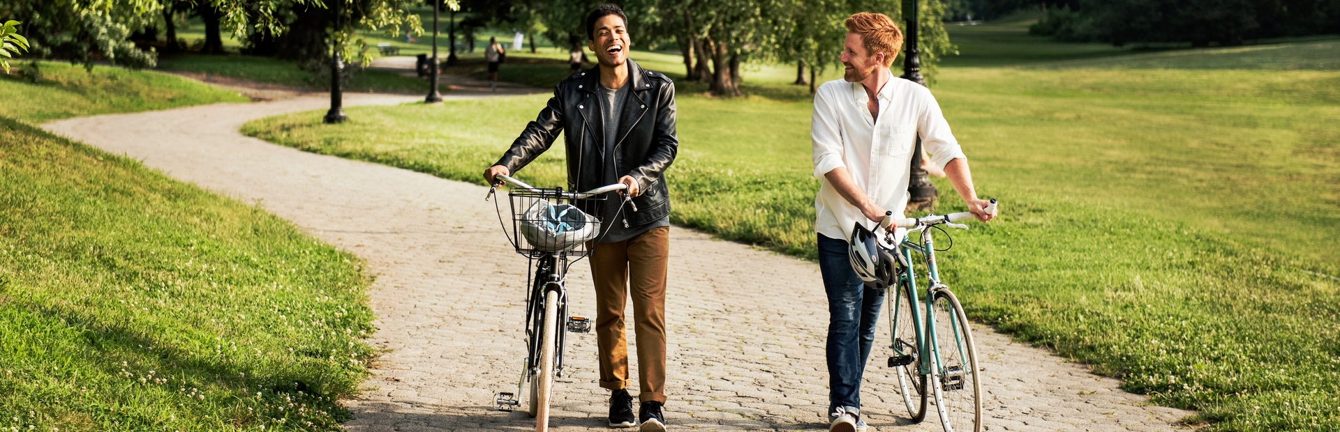 Friends walking with bikes in a park on a sunny day