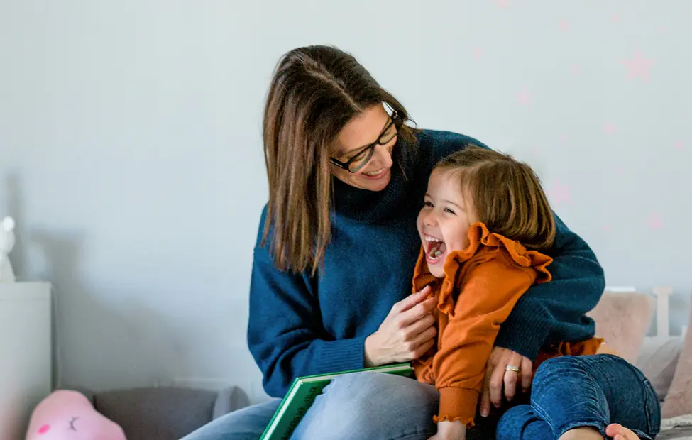 A still of a mother and daughter sharing laughter in a children`s room