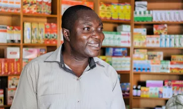 A pharmacist and his son welcoming a client in a drugstore in Ghana