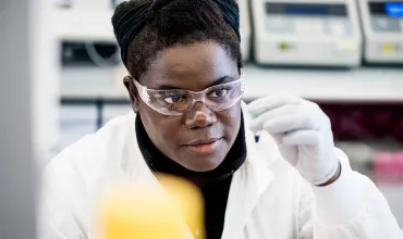 A female research scientist in a lab looking at a sample