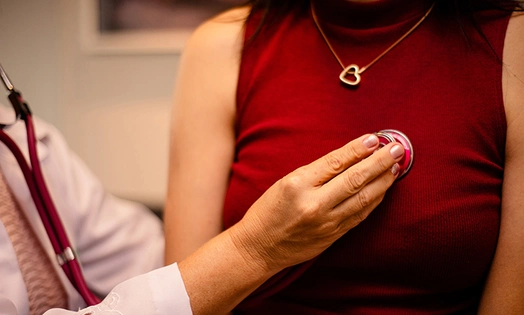 A doctor placing stethoscope on woman's chest 