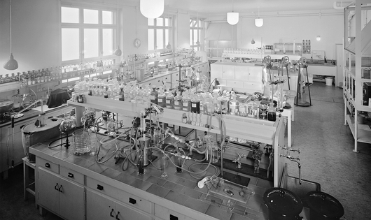 Large laboratory room in Basel with multiple benches, glassware, and equipment arranged in organized rows.