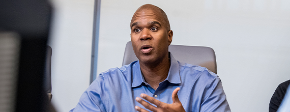 A black Novartis associate leading a meeting in a board room