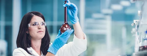 A Novartis Quality associate looking at flask in a laboratory