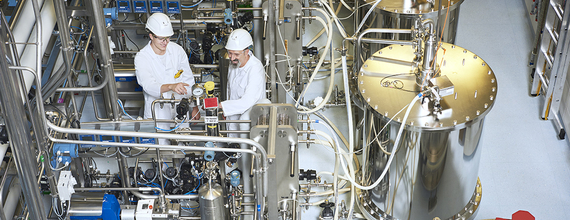 Two engineers are examining production equipment.