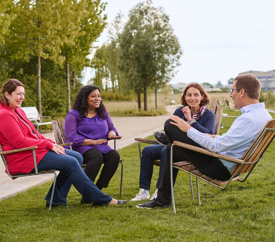 Four business people discussing while sitting in a park in the Novartis Basel campus