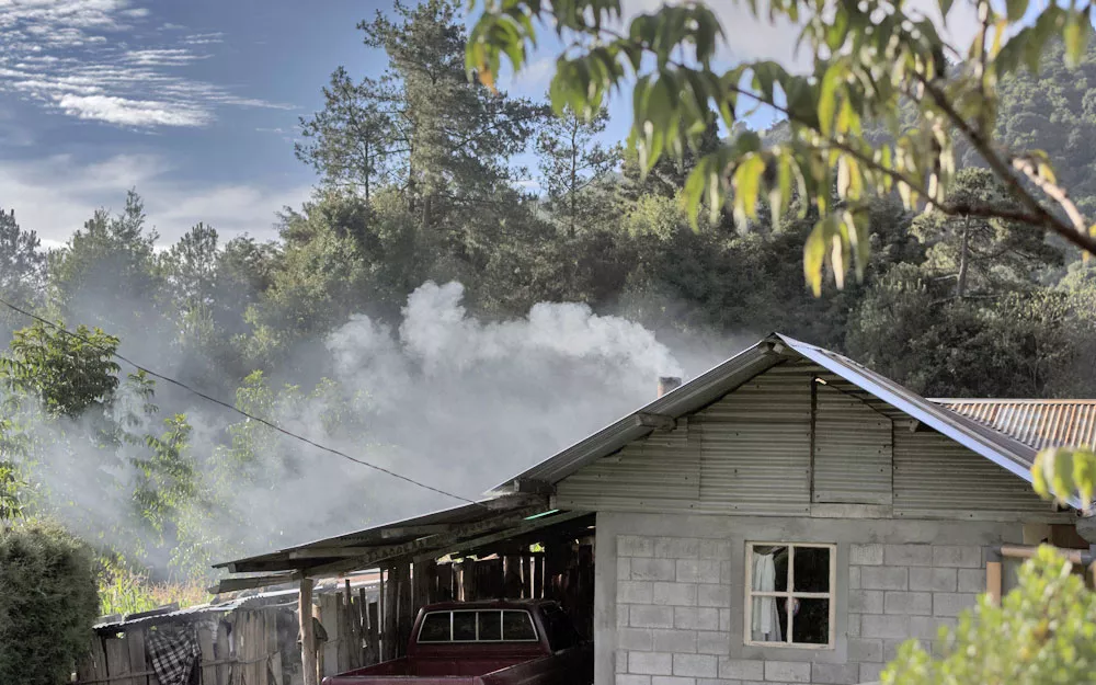 Smoke from fires used for cooking and heating rises from a house.
