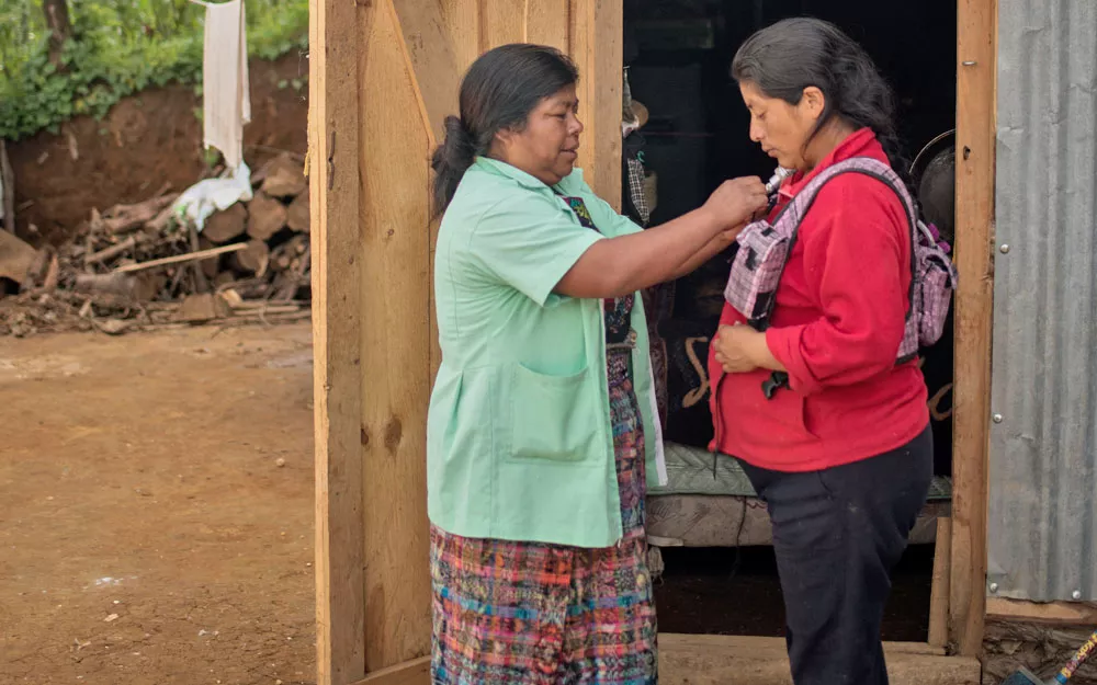 Field worker Expedita Ramírez Marroquín fits a woman with a vest to monitor levels of carbon monoxide. 