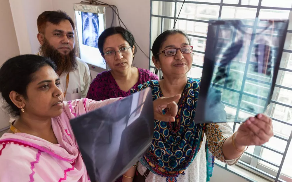 The medical team, including deputy project coordinator Dr. Kamrun Nahar (left), examines X-rays at the Kamalapur clinic.
