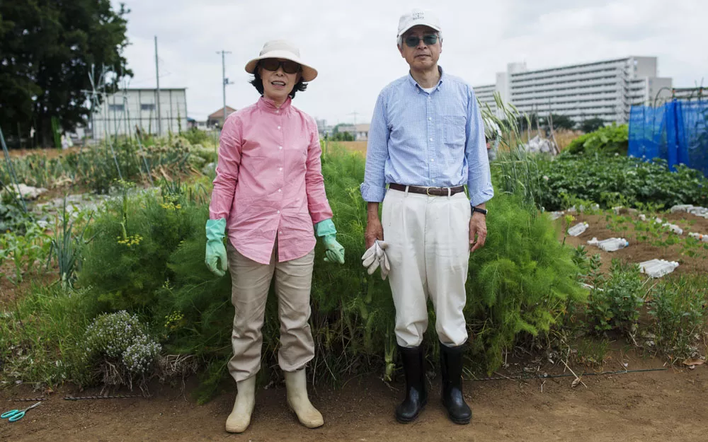 Hideo Takahashi and his wife stand in front of their vegetable plot.