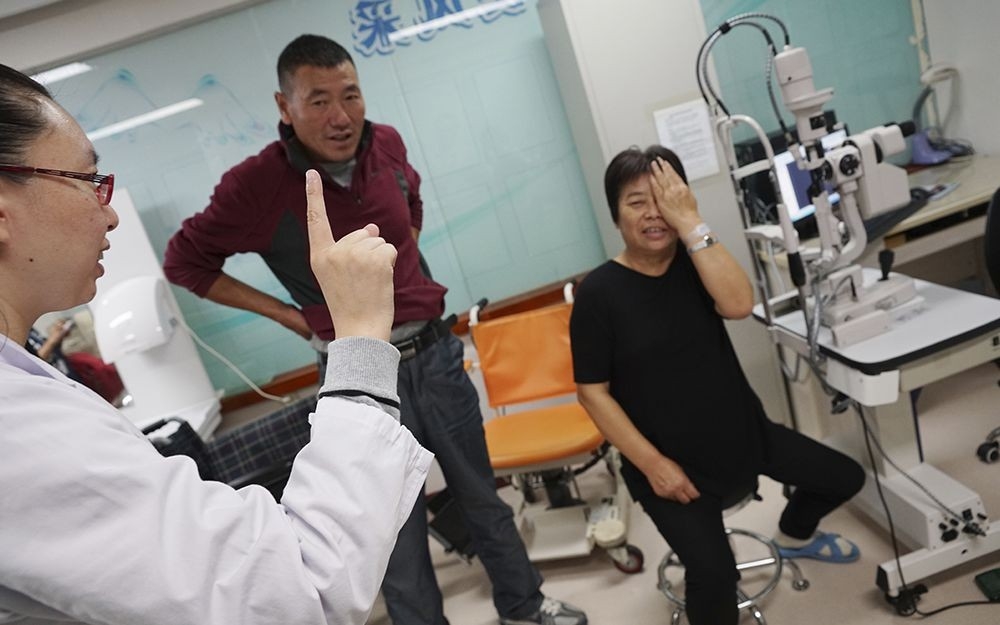 A doctor administers an eye test post-operation