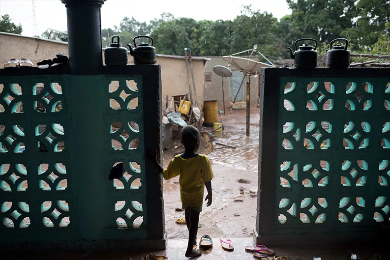 A young child watches the rain in the village of Bougoula.