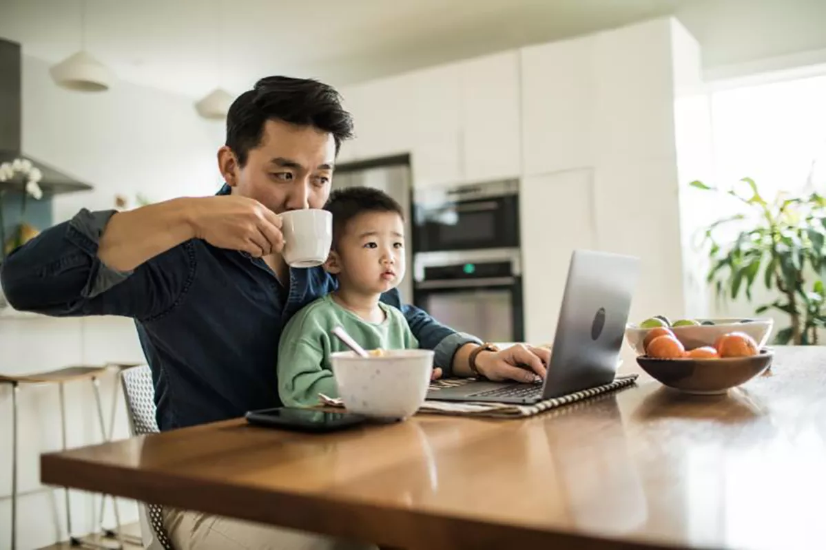 A man and child drinking infront of a laptop