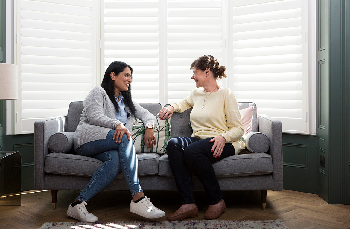 Two smiling female friends chatting on a sofa