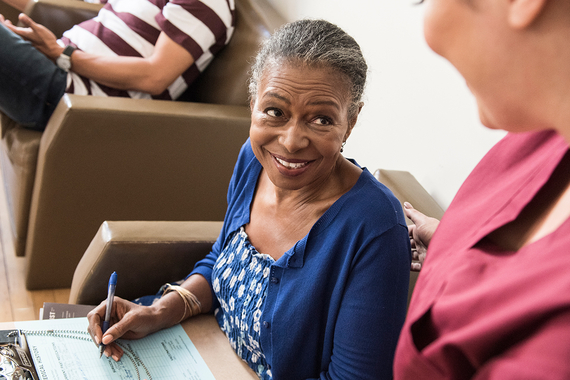 Female patient smiles at female HCP in waiting room of doctor’s office