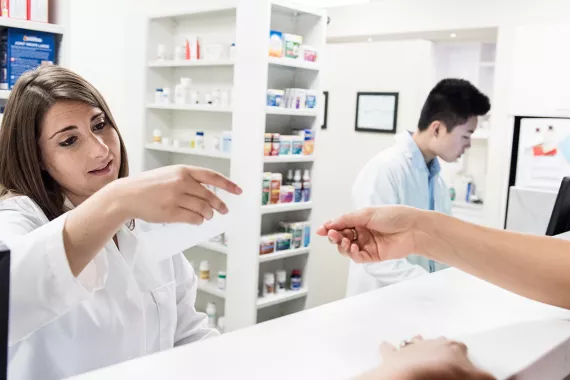 Female pharmacist reads customer’s prescription at pharmacy