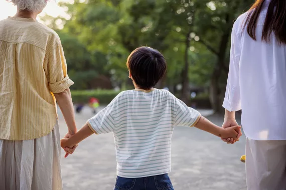 Young child holding parent and grandparents hands