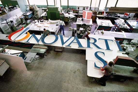 Several people working at assembling the big letters forming "Novartis" that will be installed at the top of a building on the Novartis Basel campus