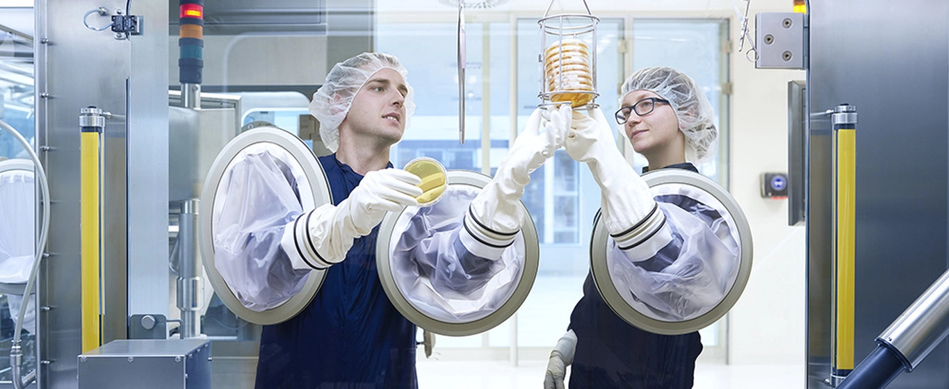 Two production specialists working with a complex manufacturing machine 
