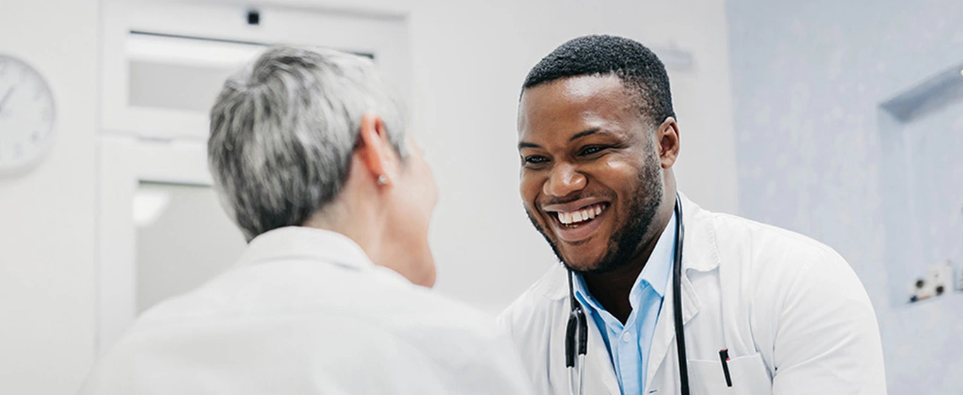 Medical professional and patient smiling and holding hands 