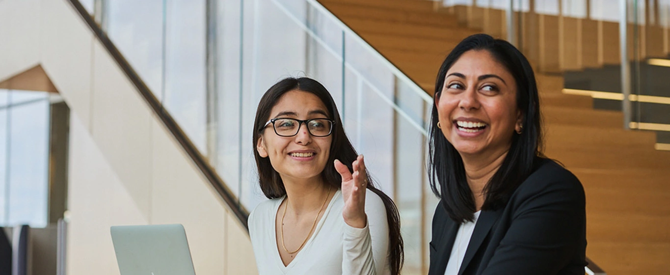 Two smiling business women meeting and working on a laptop