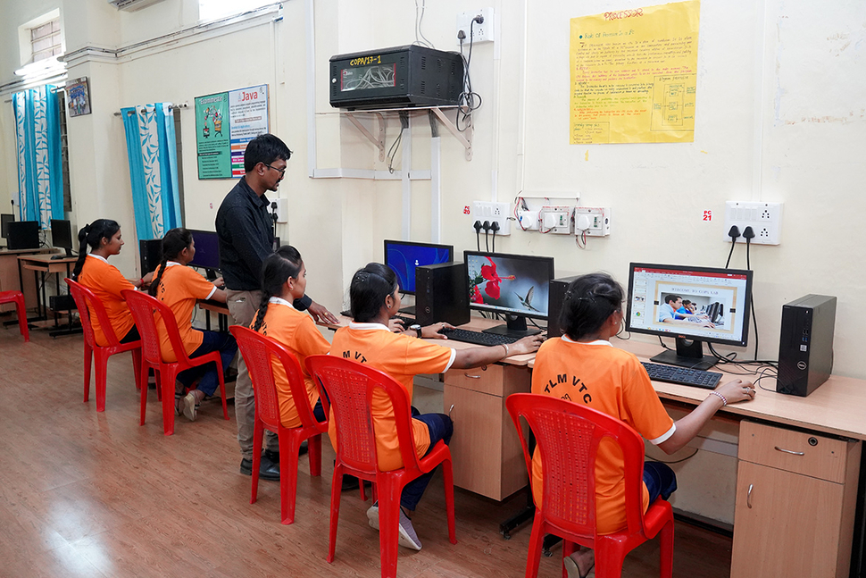 An instructor oversees an IT class in India.