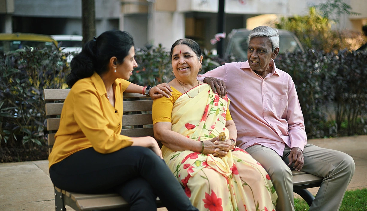 Adult daughter talking to her senior parents on a bench in a park