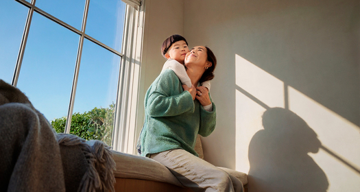 Mother and son cuddling on a couch in front of a window