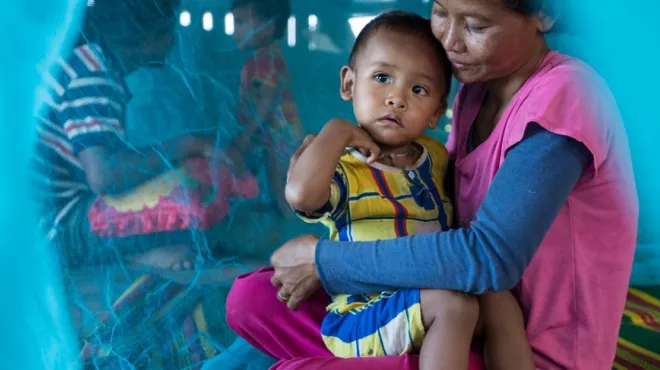 A mother and her child sit under their new insecticide-treated net in Prongyeang, Kanthout commune, Cambodia