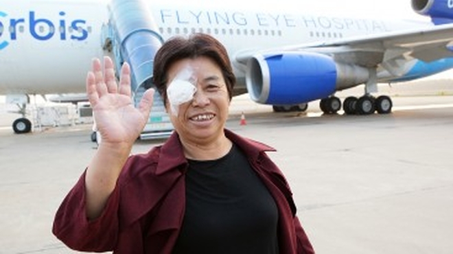 Mrs. Cao waves to the camera after exiting the flying hospital post-operation