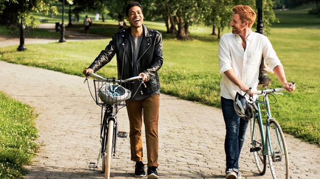 Friends walking with bikes in a park on a sunny day Friends walking with bikes in a park on a sunny day