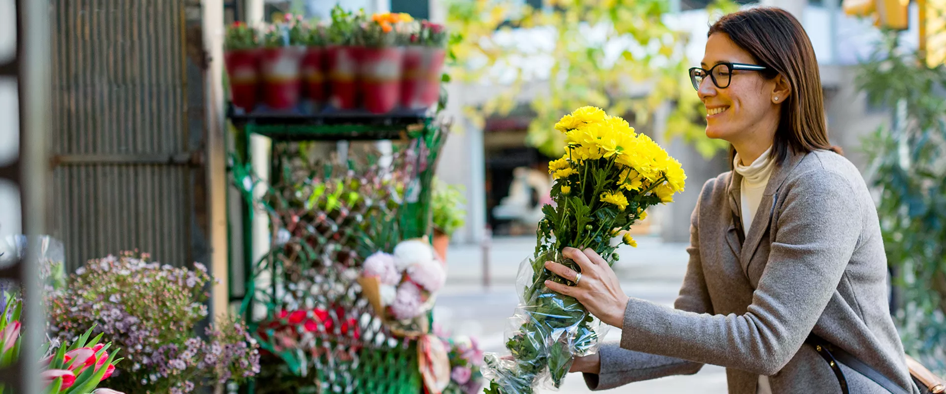 A woman holding a bunch of flowers outside a flowershop