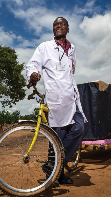 HCP wearing a medical coat pulling a cart bicycle in rural african village