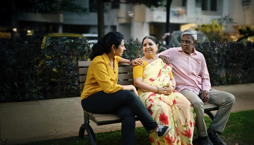 Adult daughter talking to her senior parents on a bench in a park