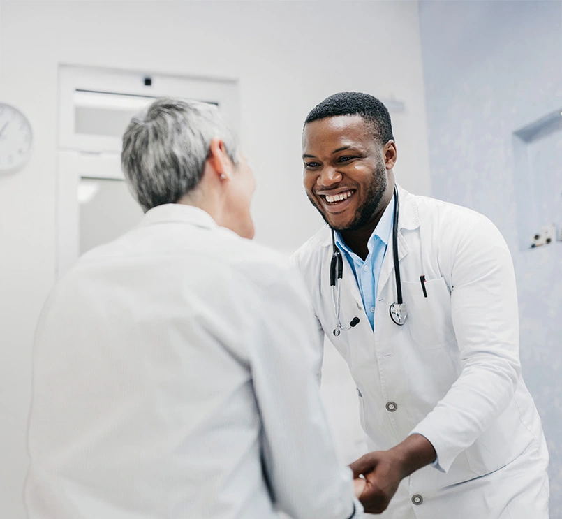 Medical professional and patient smiling and holding hands 