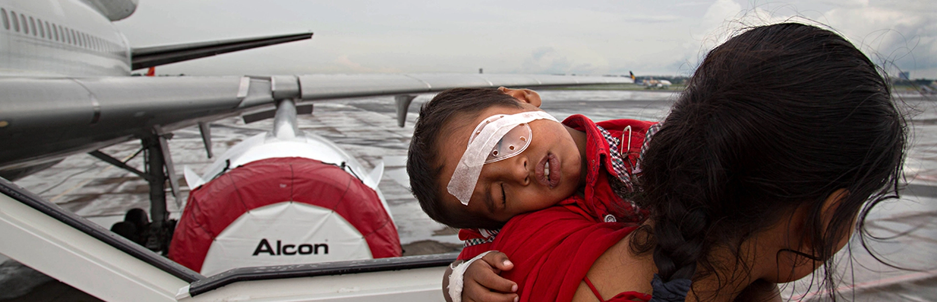 Woman carrying child with eye bandage off airplane
