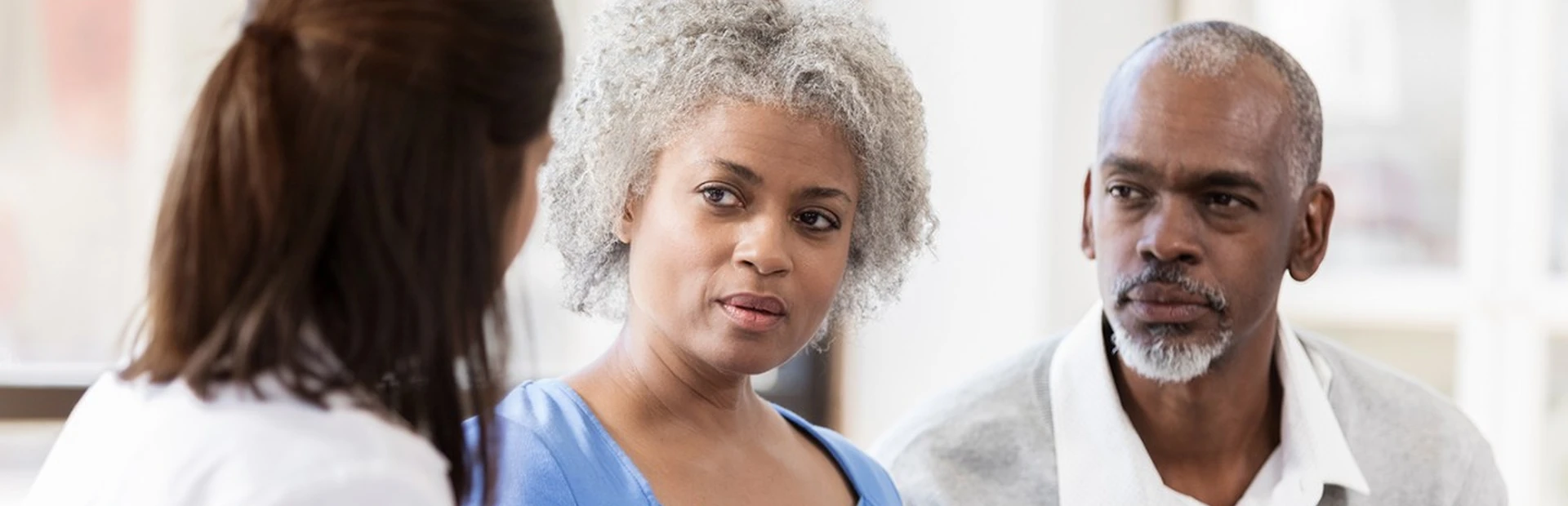 A woman, accompanied by her caregiver, shares her experiences with a doctor.