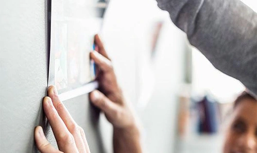 Hands hanging a piece of paper on the wall