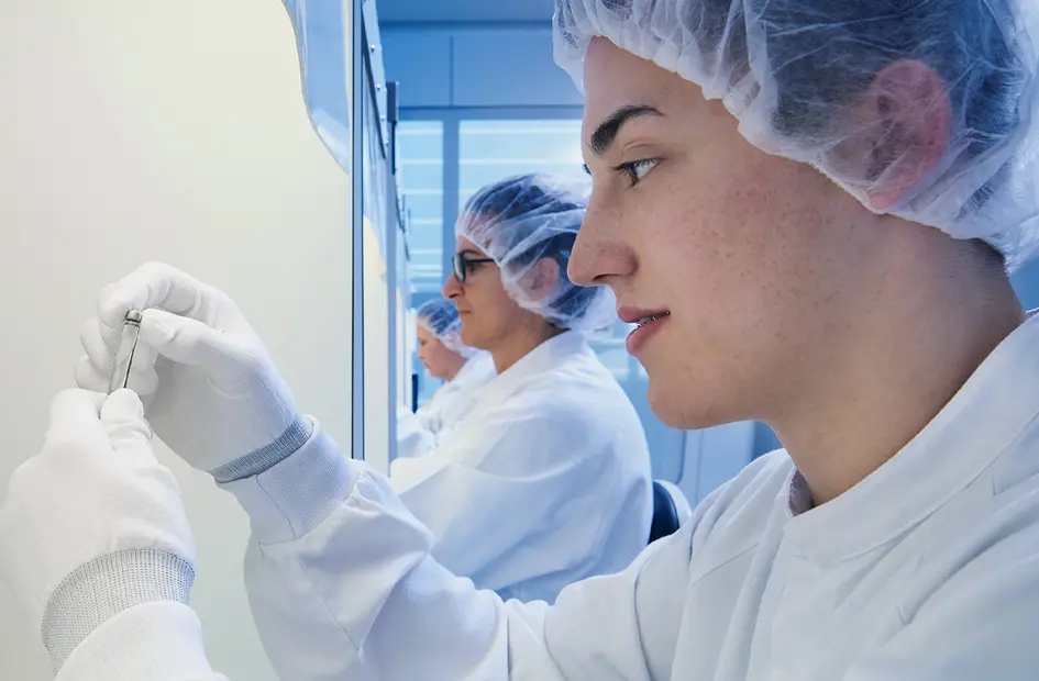 Side-ways view of scientists holding vials in a laboratory