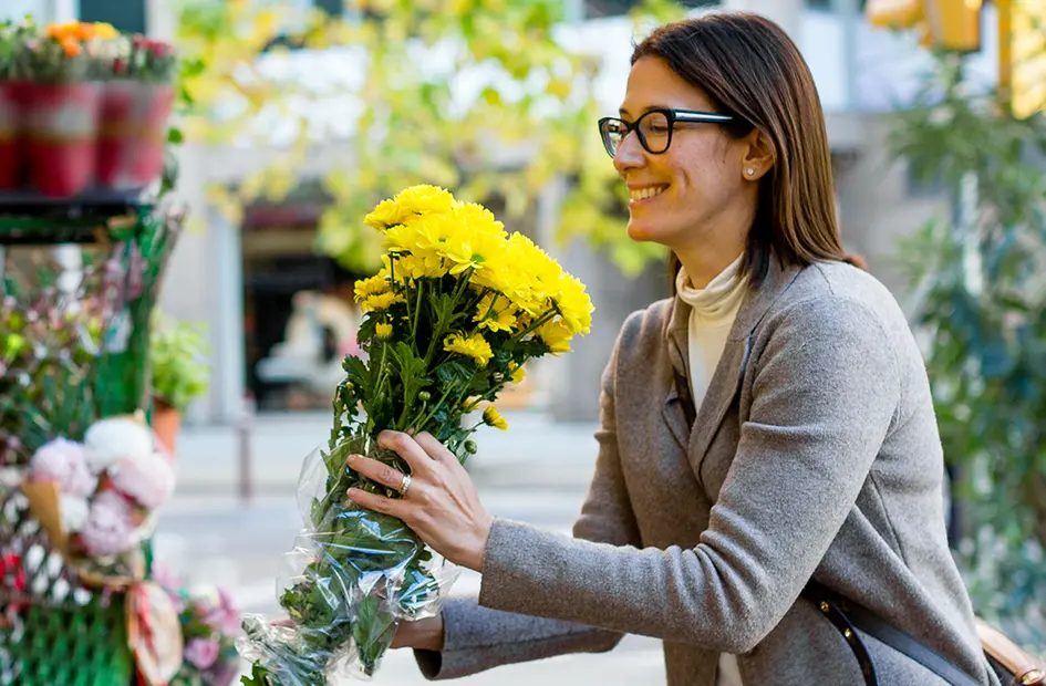 A woman holding a bunch of flowers outside a flowershop