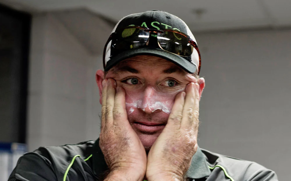 Mr. Caddies generously applies sunscreen to his face.