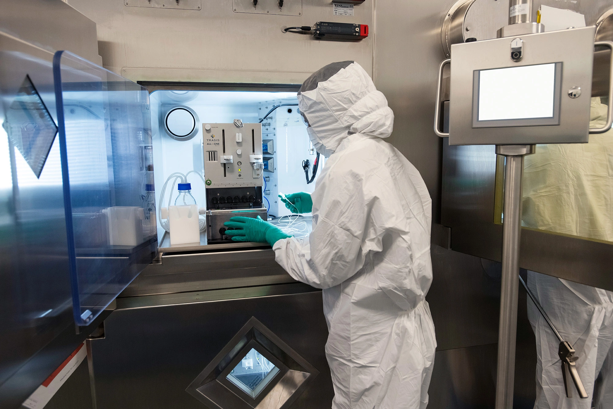 Associate in full personal protective equipment using specialized equipment on the radioligand therapy production line
