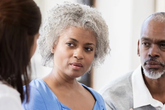 A woman, accompanied by her caregiver, shares her experiences with a doctor.