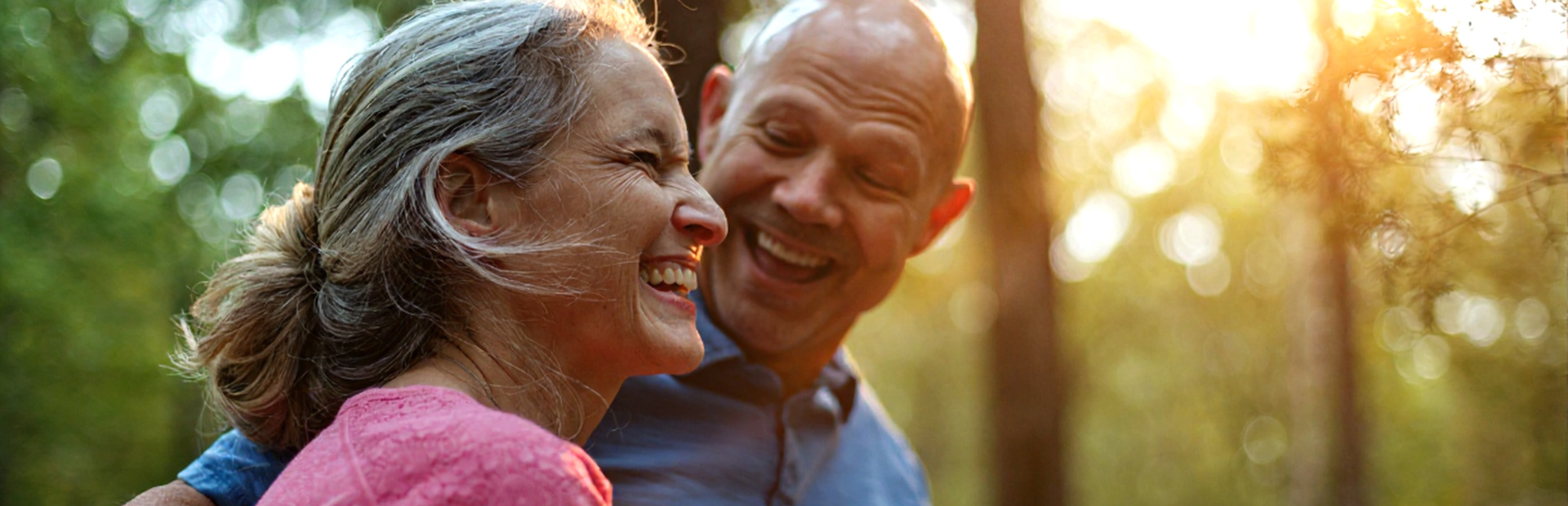 Elderly coupling hugging in sunlit forest