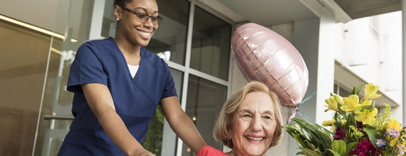 HCP pushing smiling patient in wheelchair