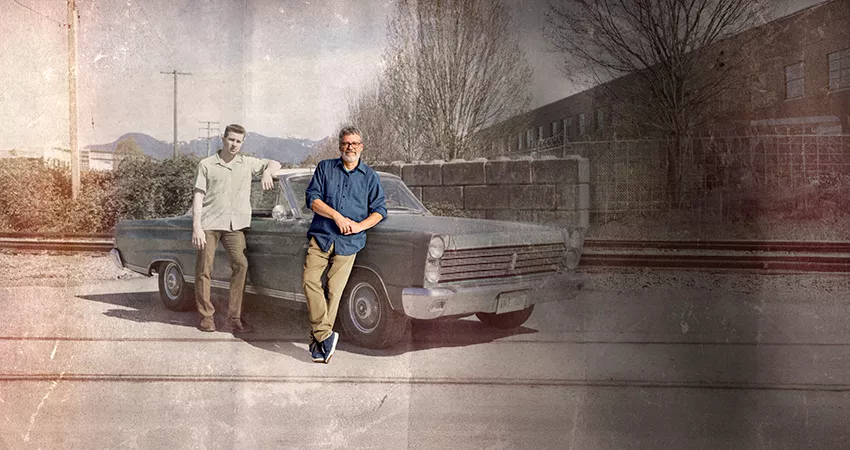 Older man leaning on car (convertible) while his younger self is behind him, somewhat as a shadow