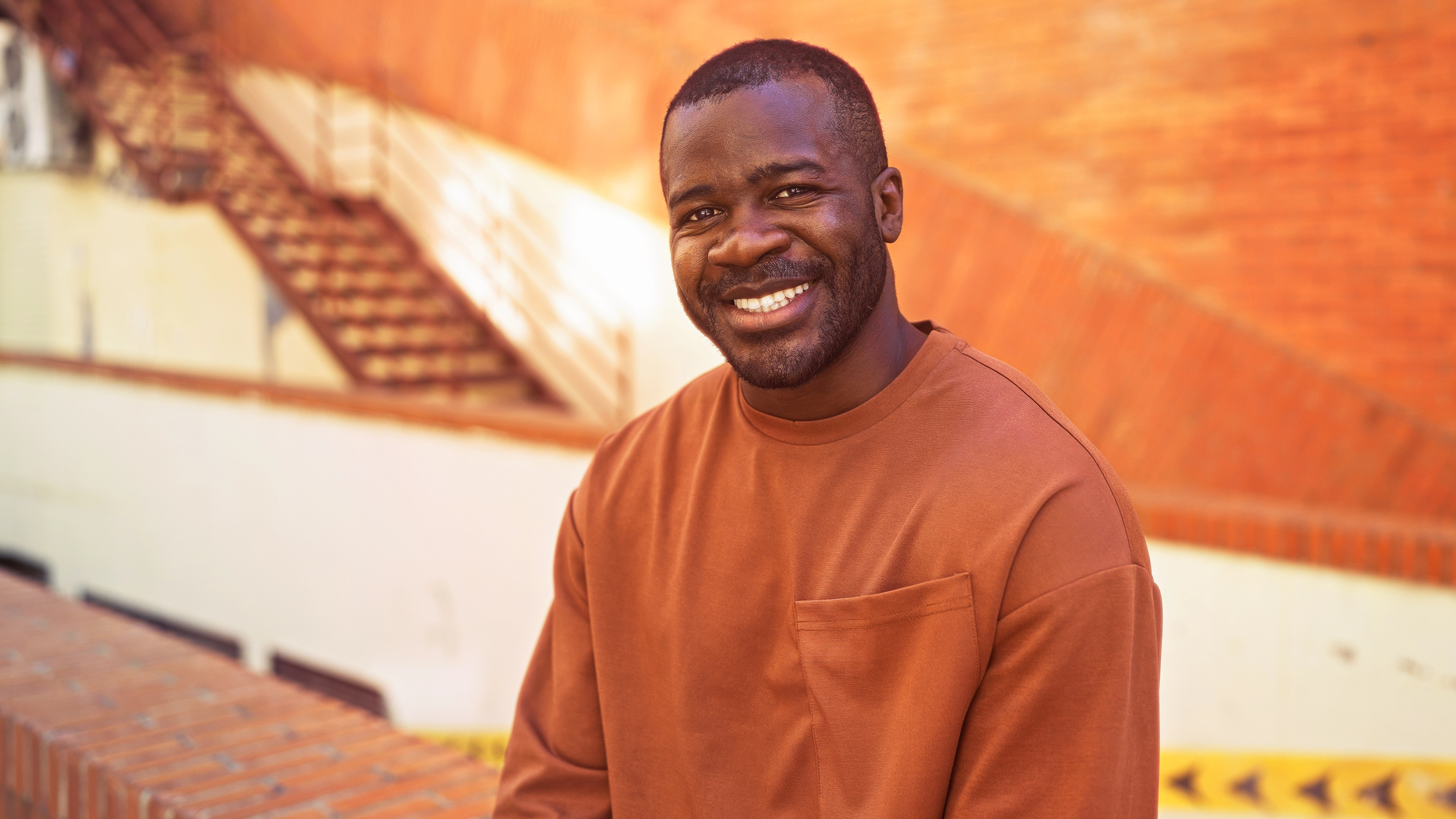 A smiling man sitting outside.